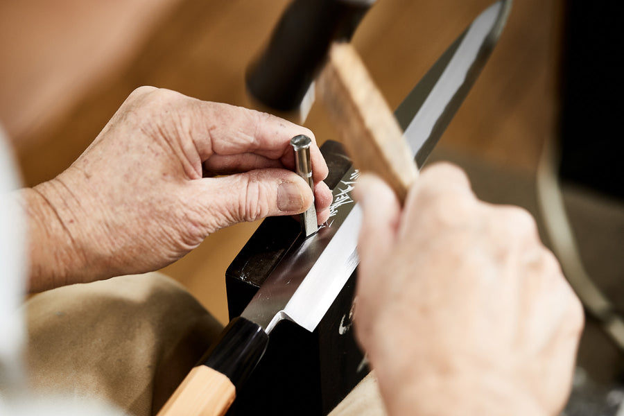 A photo of a craftsman making a knife.